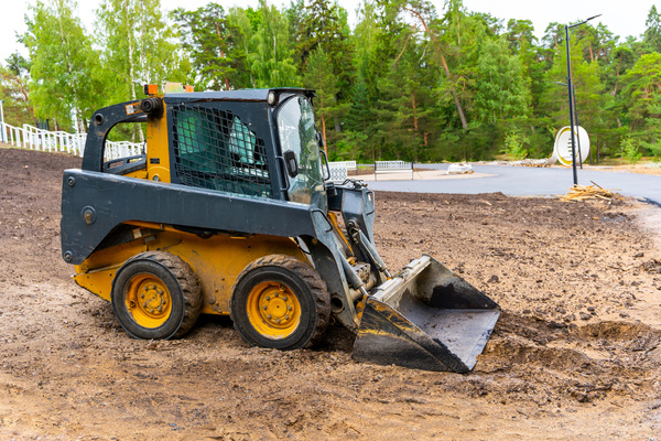 A loader with a bucket clears the site for construction