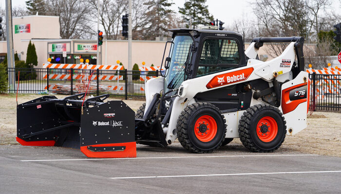 Steer loader with Bobcat Kage snowplow sits outside unused