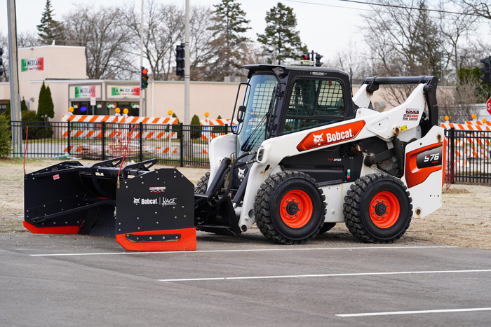 Steer loader with Bobcat Kage snowplow sits outside unused