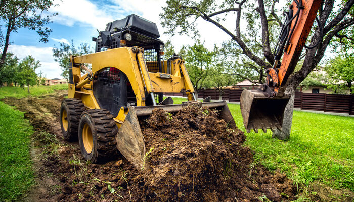 Yellow machinery working with earth, moving soil and doing landscaping works