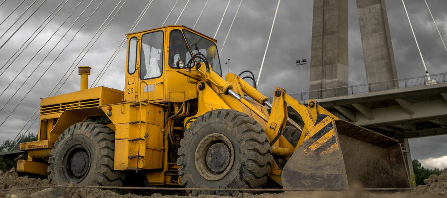 A yellow bulldozer next to a bridge
