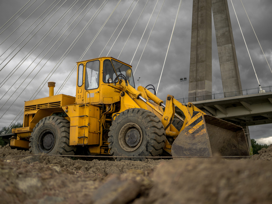 A yellow bulldozer next to a bridge