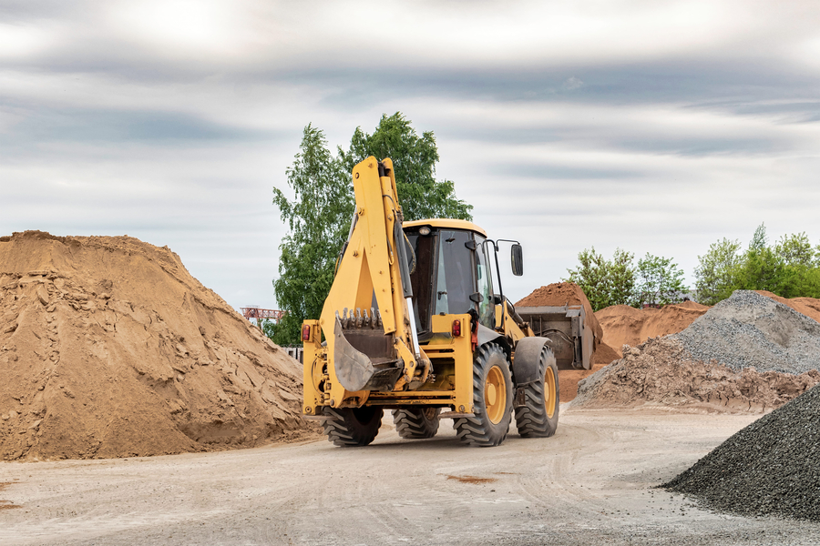 Powerful wheel loader or bulldozer at the construction site. Loader transport sand in a storage bucket. Powerful modern equipment for earthworks